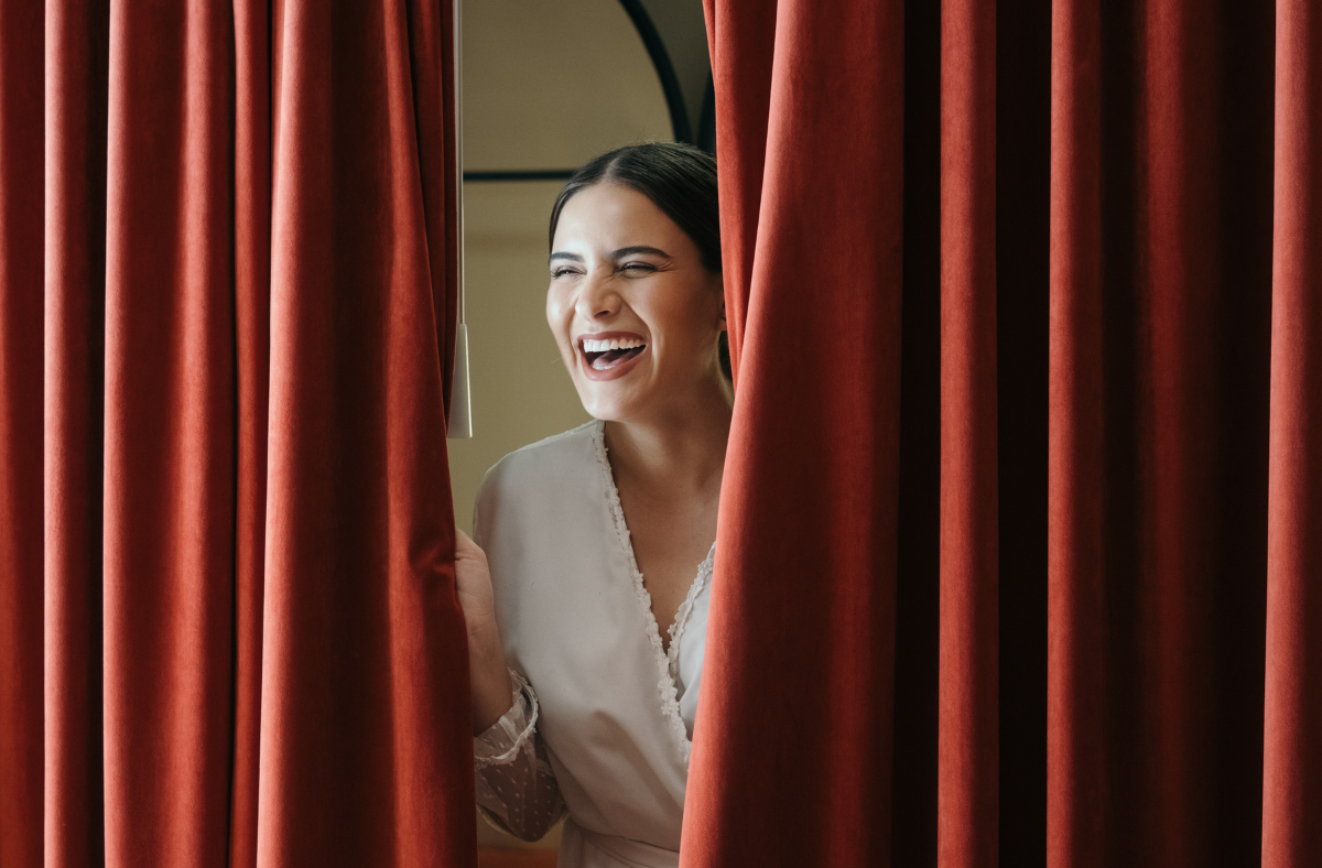 Women laughing behind red curtain